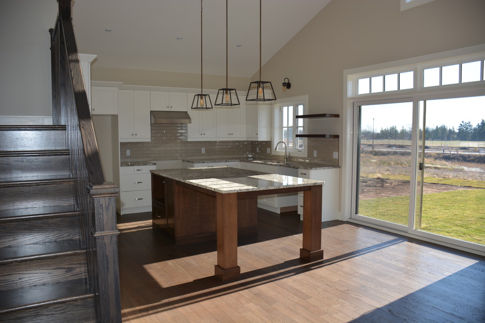 Mid-sized transitional u-shaped light wood floor eat-in kitchen photo in Toronto with a double-bowl sink, shaker cabinets, white cabinets, granite countertops, gray backsplash, subway tile backsplash, stainless steel appliances and an island