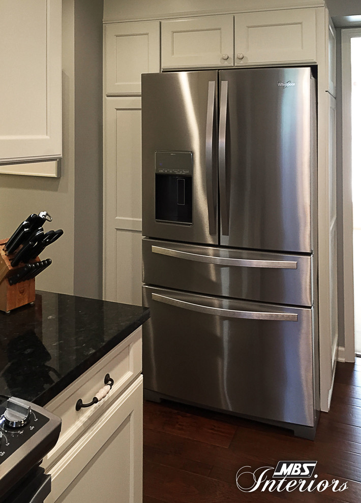 Example of a mid-sized transitional l-shaped medium tone wood floor and brown floor eat-in kitchen design with an undermount sink, white cabinets, granite countertops, gray backsplash, subway tile backsplash, stainless steel appliances, an island and recessed-panel cabinets