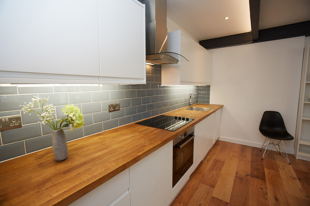 Design ideas for a small contemporary single-wall open plan kitchen in London with a single-bowl sink, flat-panel cabinets, white cabinets, laminate benchtops, grey splashback, ceramic splashback, panelled appliances, laminate floors and no island.