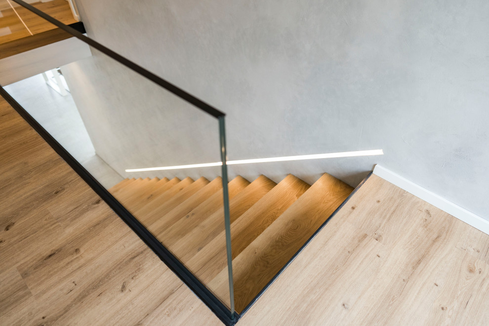 This is an example of a contemporary wood glass railing staircase in Munich.