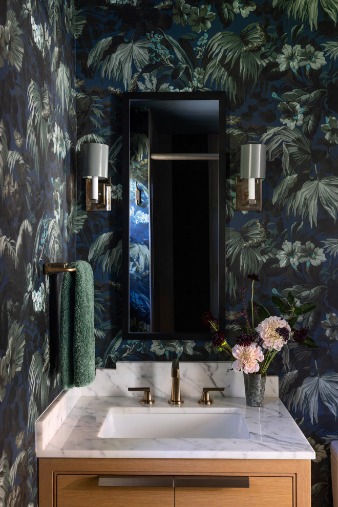 Inspiration for a small retro cloakroom in San Francisco with beaded cabinets, medium wood cabinets, a two-piece toilet, multi-coloured walls, light hardwood flooring, a submerged sink, marble worktops, beige floors, white worktops, a floating vanity unit and wallpapered walls.
