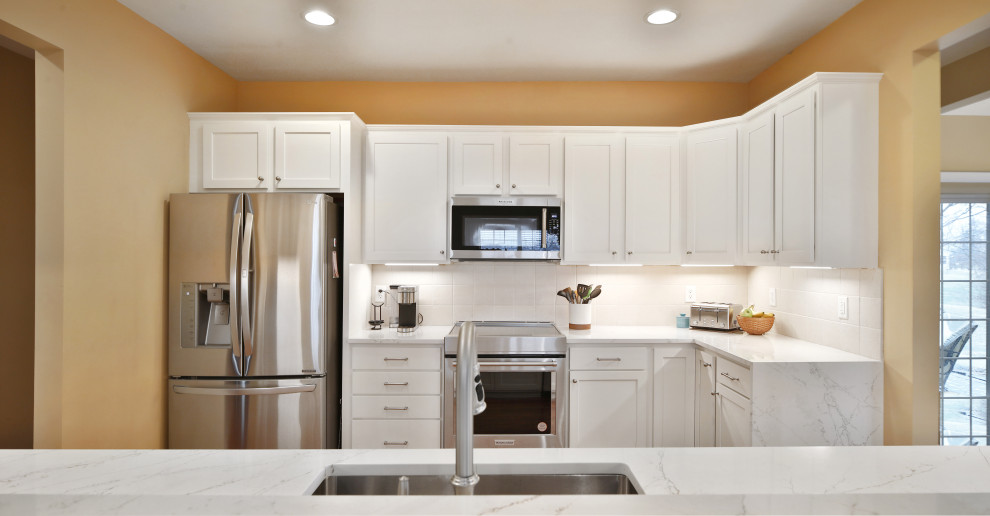 Example of a mid-sized transitional galley medium tone wood floor and brown floor enclosed kitchen design in Columbus with a single-bowl sink, shaker cabinets, white cabinets, quartz countertops, white backsplash, ceramic backsplash, stainless steel appliances, no island and white countertops