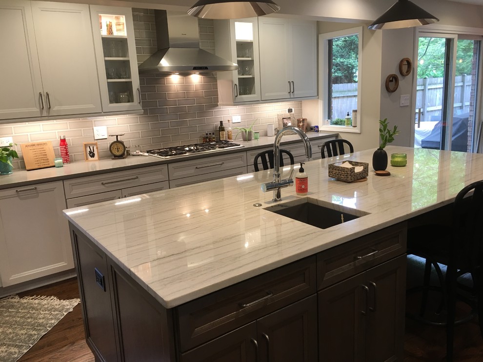 Open concept kitchen - large transitional u-shaped dark wood floor and brown floor open concept kitchen idea in Chicago with an undermount sink, flat-panel cabinets, white cabinets, quartz countertops, gray backsplash, ceramic backsplash, stainless steel appliances, an island and gray countertops