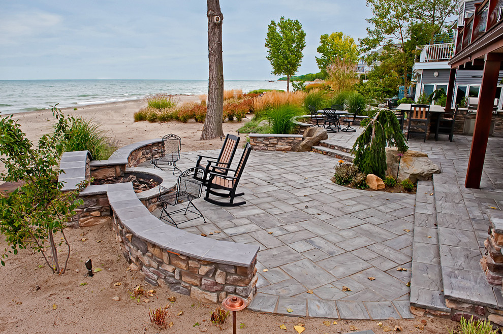 This is an example of a large modern backyard patio in Other with an outdoor kitchen, natural stone pavers and no cover.