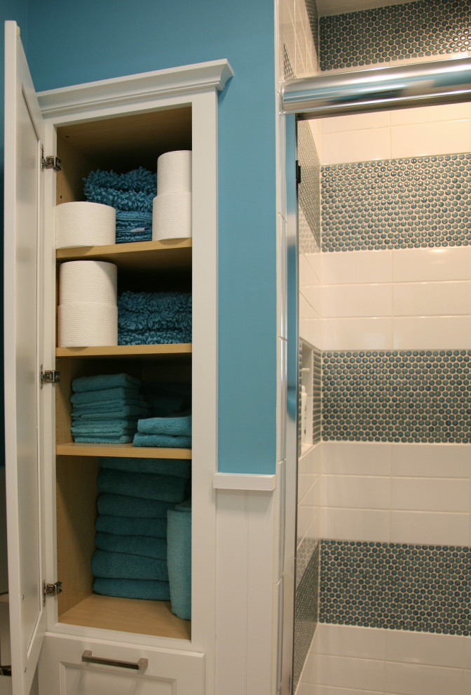 Photo of a mid-sized beach style kids bathroom in Milwaukee with flat-panel cabinets, blue cabinets, an alcove shower, a one-piece toilet, blue tile, ceramic tile, blue walls, ceramic floors, an undermount sink, engineered quartz benchtops, beige floor, a sliding shower screen, white benchtops, an enclosed toilet, a double vanity and a built-in vanity.