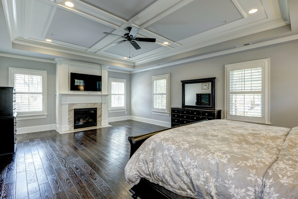 Photo of a large traditional master bedroom in DC Metro with grey walls, medium hardwood floors, a standard fireplace and a wood fireplace surround.