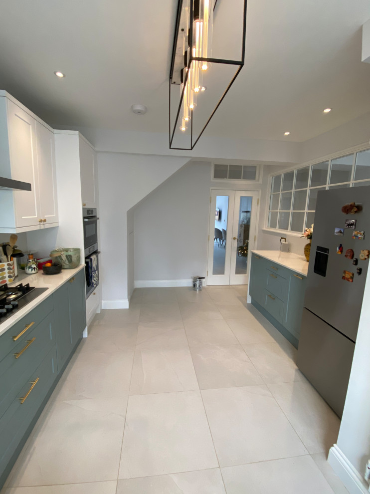 Large contemporary galley kitchen/diner in London with quartz worktops, white splashback, porcelain flooring and no island.