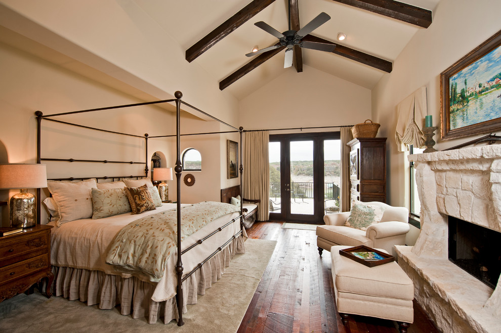 Design ideas for an expansive traditional master bedroom in Austin with white walls, dark hardwood floors, a standard fireplace, a stone fireplace surround and brown floor.