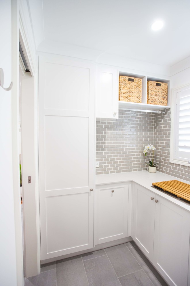 This is an example of a small traditional l-shaped dedicated laundry room in Brisbane with a single-bowl sink, shaker cabinets, white cabinets, quartz benchtops, white walls, porcelain floors, grey floor and white benchtop.