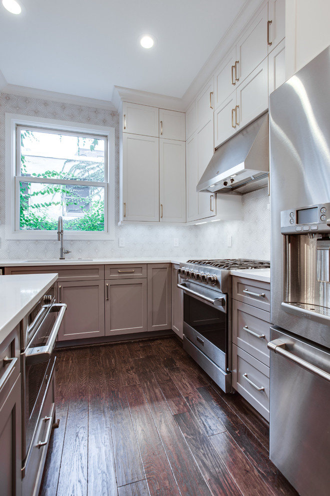 Large transitional l-shaped medium tone wood floor and brown floor eat-in kitchen photo in DC Metro with an undermount sink, shaker cabinets, white cabinets, solid surface countertops, white backsplash, ceramic backsplash, stainless steel appliances, an island and white countertops