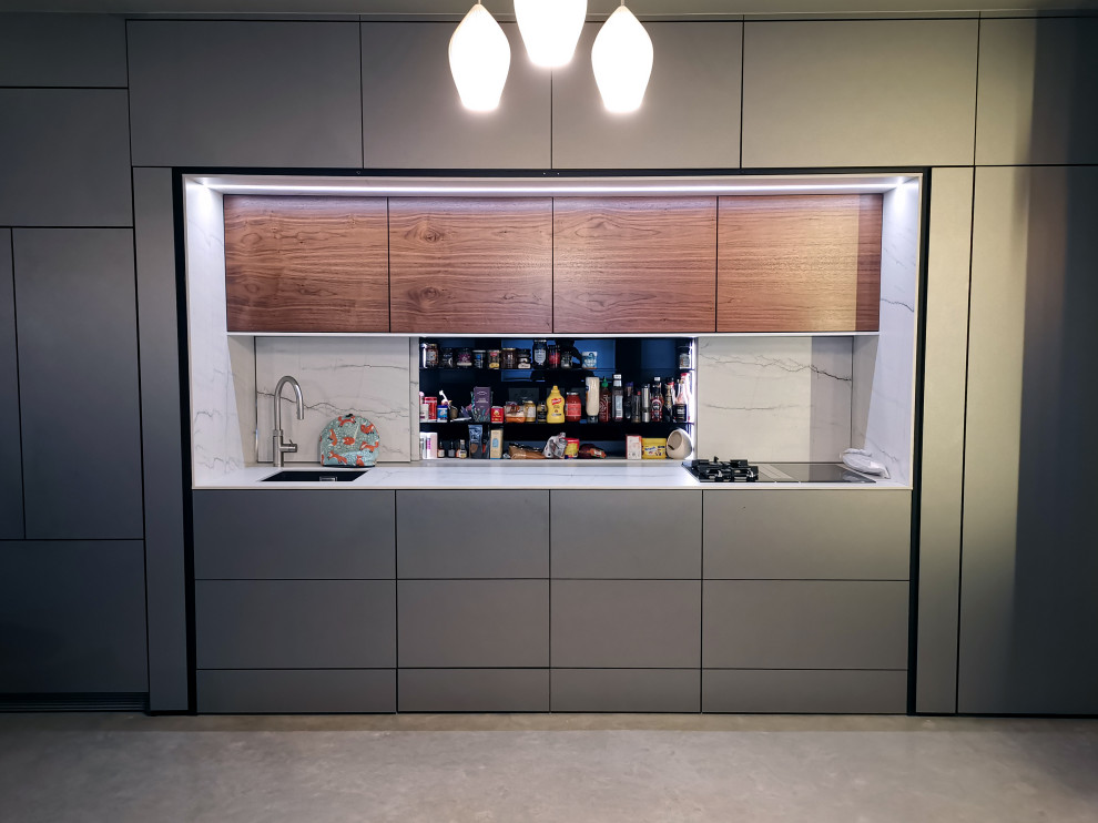 Inspiration for a small modern single-wall separate kitchen in London with a single-bowl sink, flat-panel cabinets, stainless steel cabinets, quartz benchtops, white splashback, engineered quartz splashback, black appliances, concrete floors, no island, grey floor, white benchtop and recessed.