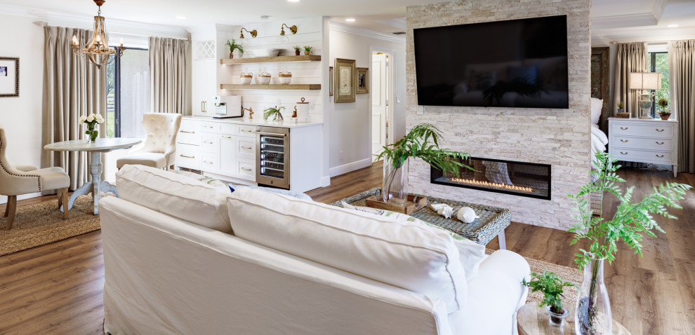 Geräumiges Landhaus Hauptschlafzimmer mit weißer Wandfarbe, Vinylboden, Tunnelkamin, Kaminumrandung aus gestapelten Steinen, braunem Boden und eingelassener Decke in Miami