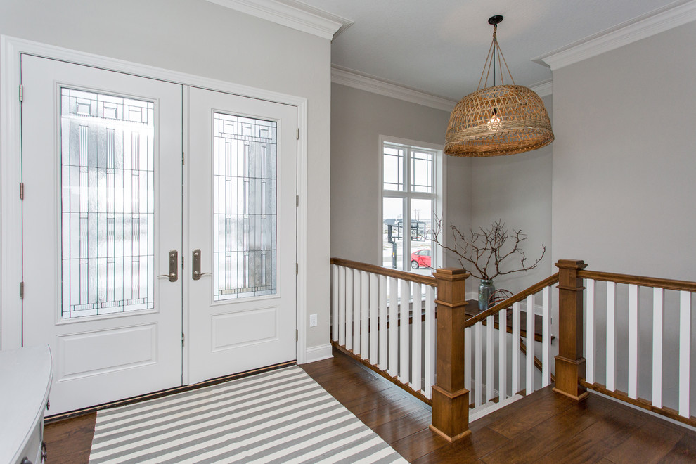 Transitional medium tone wood floor and brown floor front door photo with gray walls and a white front door