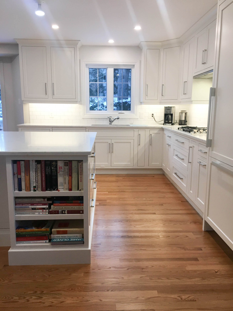 Example of a large transitional u-shaped light wood floor and beige floor eat-in kitchen design with a double-bowl sink, shaker cabinets, white cabinets, quartzite countertops, white backsplash, subway tile backsplash, stainless steel appliances, an island and white countertops