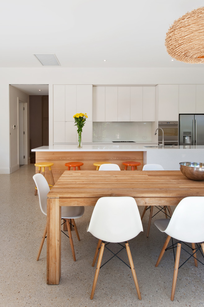 Mid-sized contemporary eat-in kitchen in Adelaide with an undermount sink, flat-panel cabinets, medium wood cabinets, quartz benchtops, white splashback, glass sheet splashback, stainless steel appliances, concrete floors and with island.