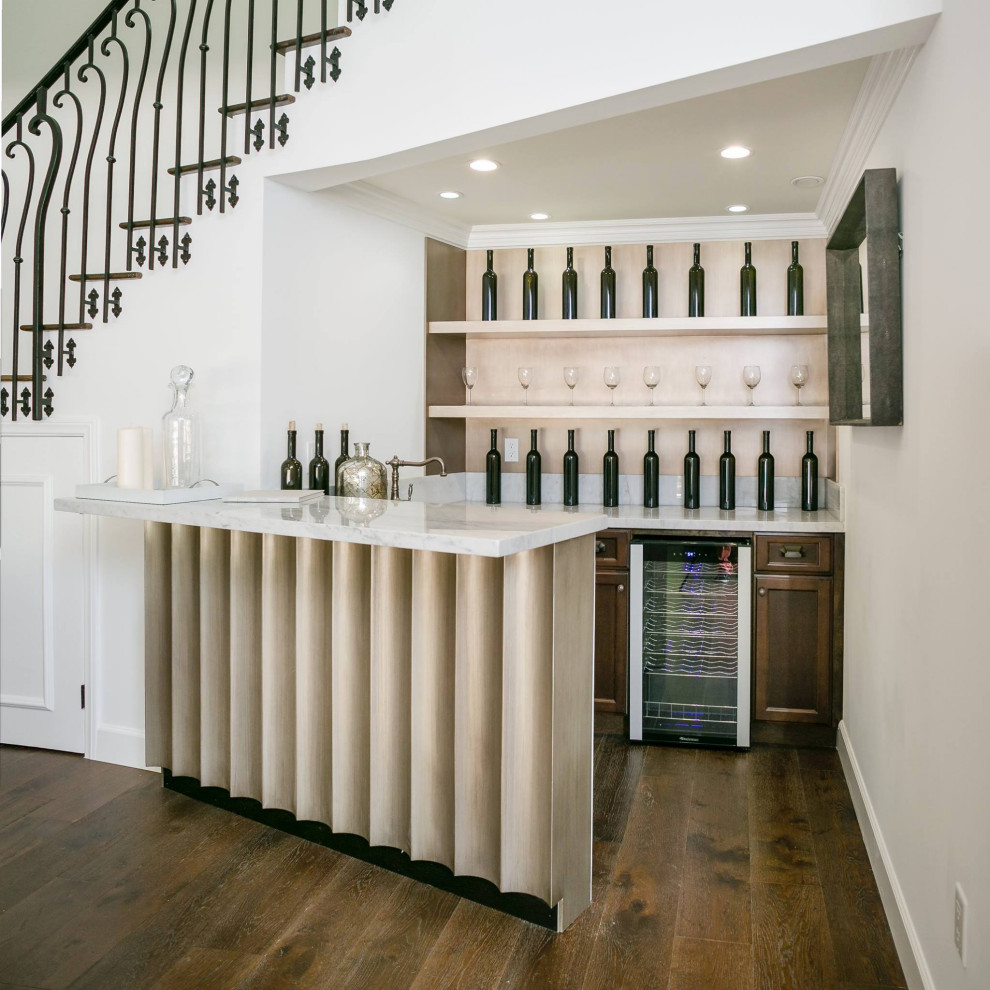 Design ideas for a mid-sized transitional u-shaped wet bar in Los Angeles with an undermount sink, recessed-panel cabinets, dark wood cabinets, marble benchtops, white splashback, marble splashback, medium hardwood floors, brown floor and white benchtop.