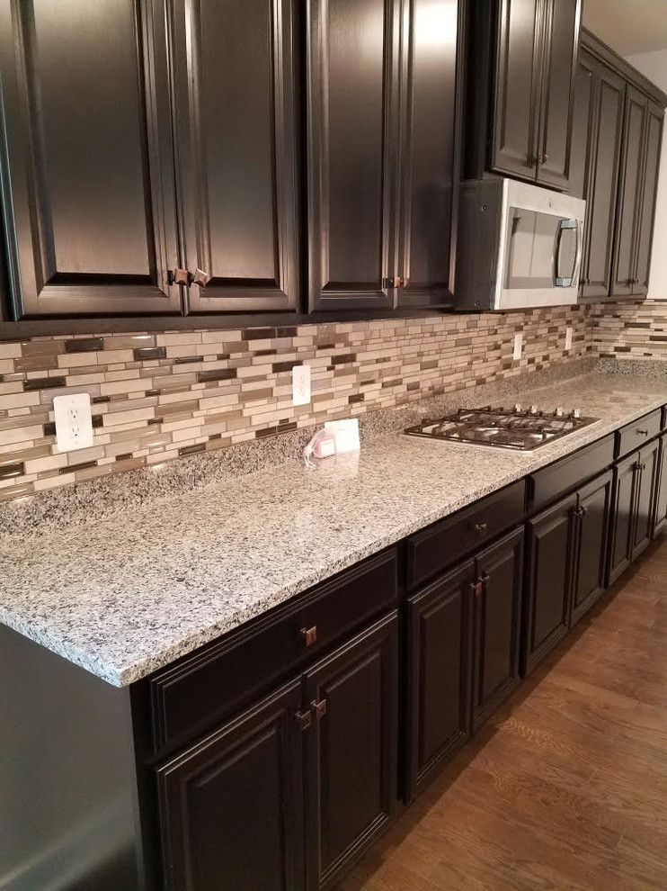 Transitional dark wood floor and brown floor eat-in kitchen photo in DC Metro with a drop-in sink, dark wood cabinets, granite countertops, multicolored backsplash, glass tile backsplash, stainless steel appliances and multicolored countertops