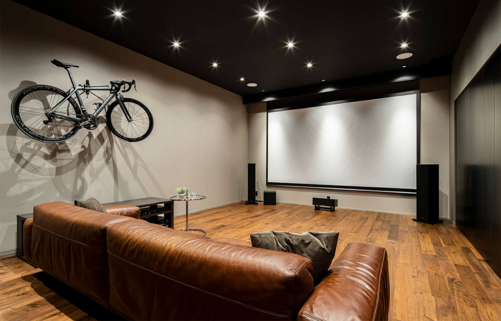 This is an example of a modern fully buried basement with a home cinema and grey walls.