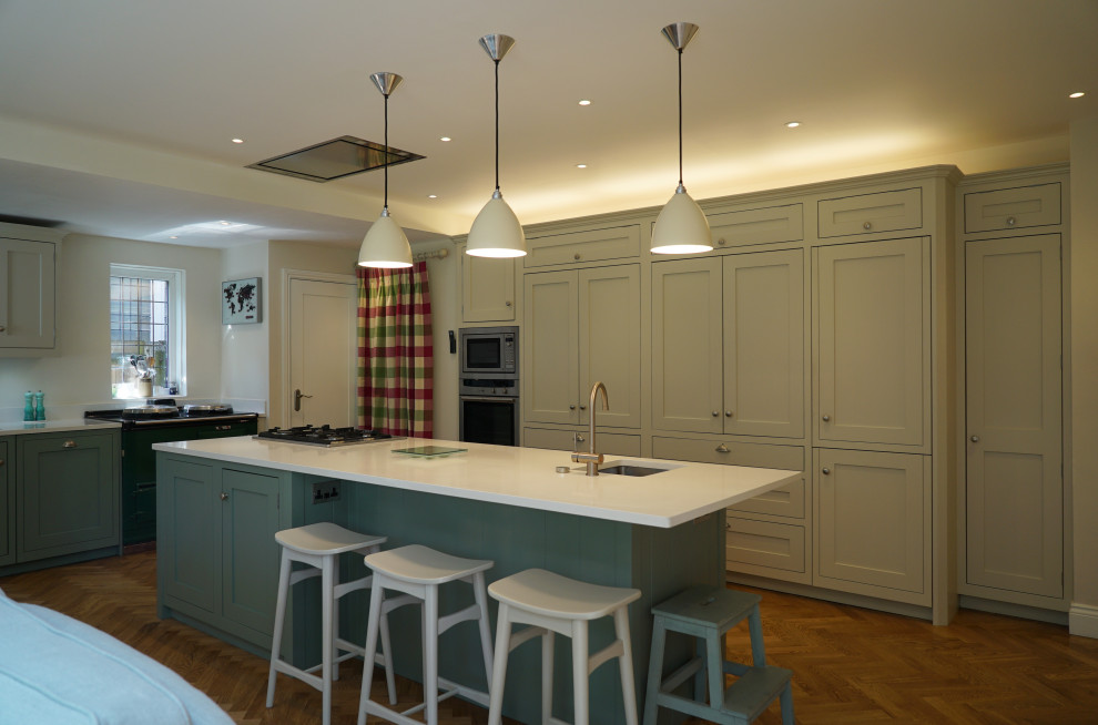 This is an example of a large contemporary l-shaped open plan kitchen in London with recessed-panel cabinets and with island.