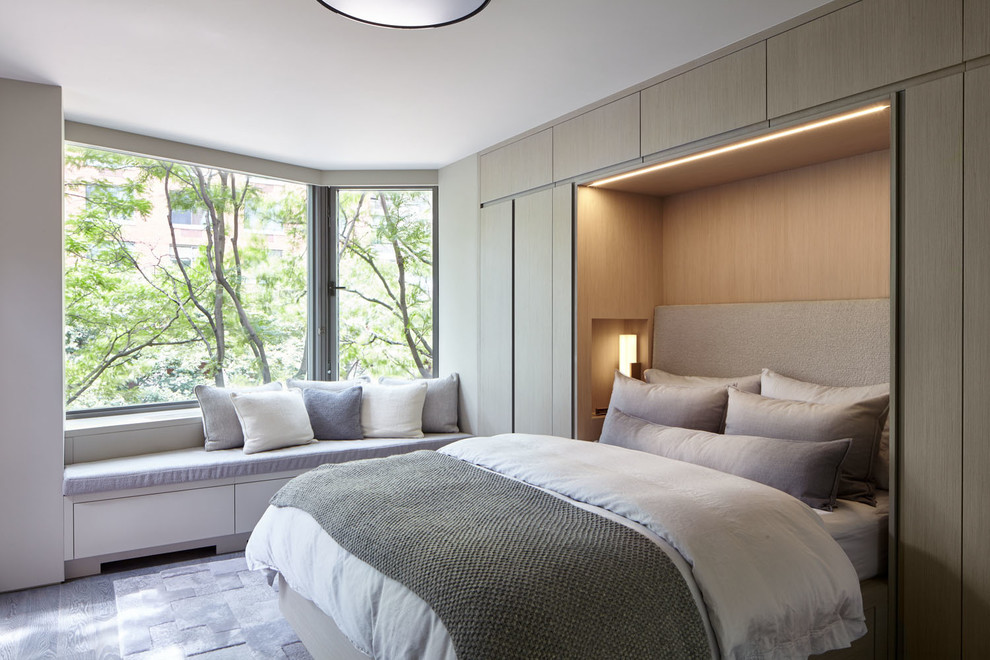 Small modern master bedroom in New York with grey walls, medium hardwood floors and grey floor.