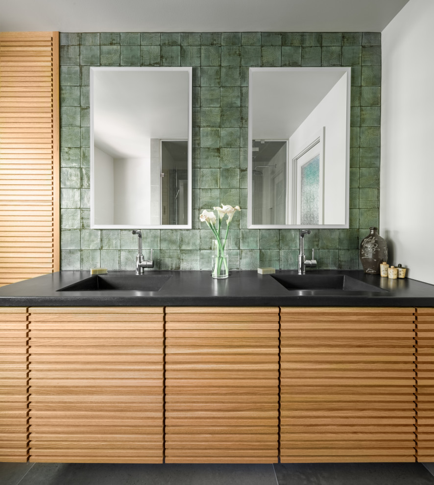 Идея дизайна: главная ванная комната в восточном стиле с светлыми деревянными фасадами, зеленой плиткой, полом из керамогранита, монолитной раковиной, столешницей из бетона, серым полом, черной столешницей, сиденьем для душа, тумбой под две раковины и подвесной тумбой