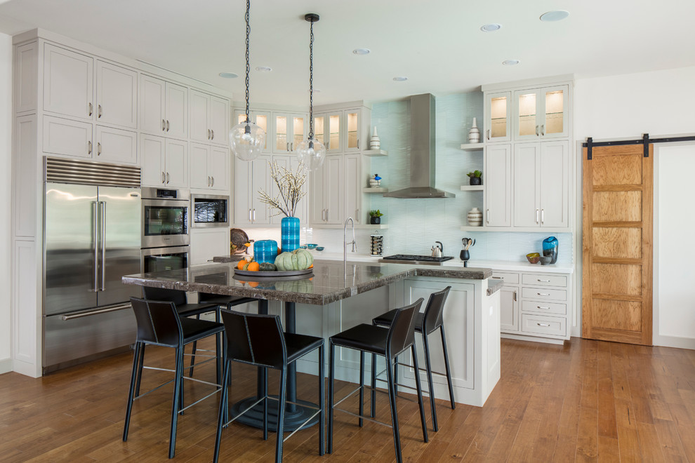 Inspiration for a transitional l-shaped kitchen in Austin with shaker cabinets, grey cabinets, blue splashback, stainless steel appliances, medium hardwood floors and with island.