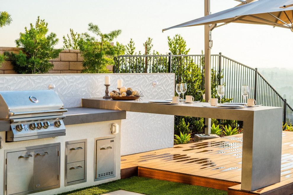 Cette image montre une terrasse en bois arrière design de taille moyenne avec une cuisine d'été et un auvent.