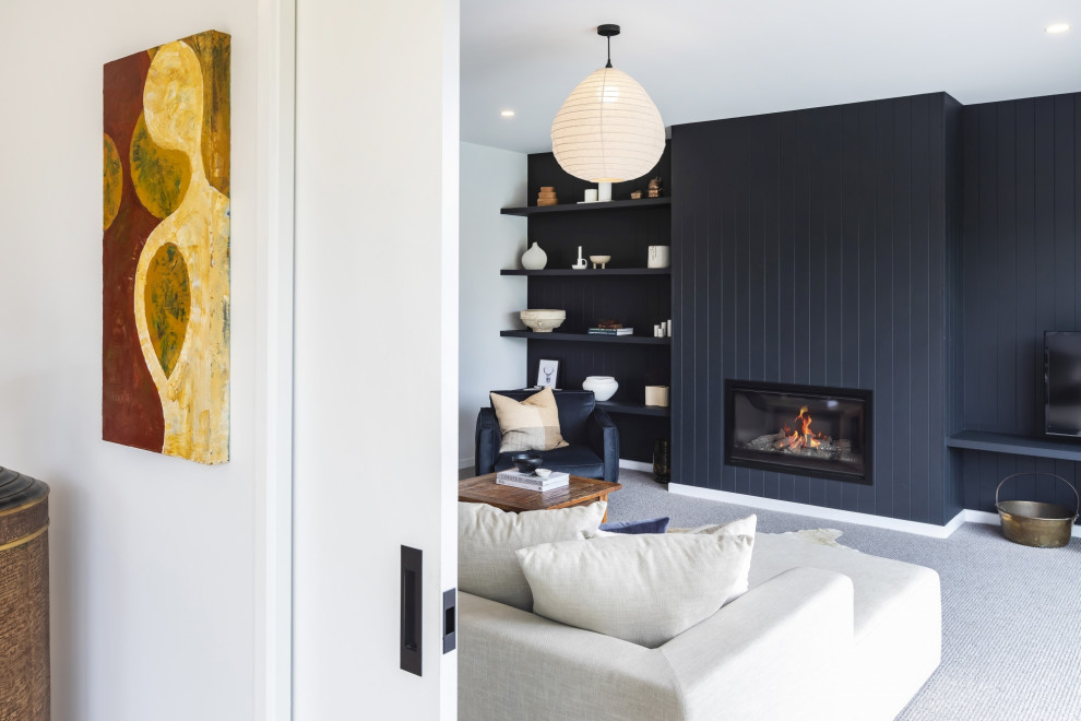 Mid-sized contemporary Enclosed living room in Christchurch With Black Walls, Carpet, a Standard Fireplace, a Wood Fireplace Surround, a Freestanding TV, Grey Floor and Wood Walls.
