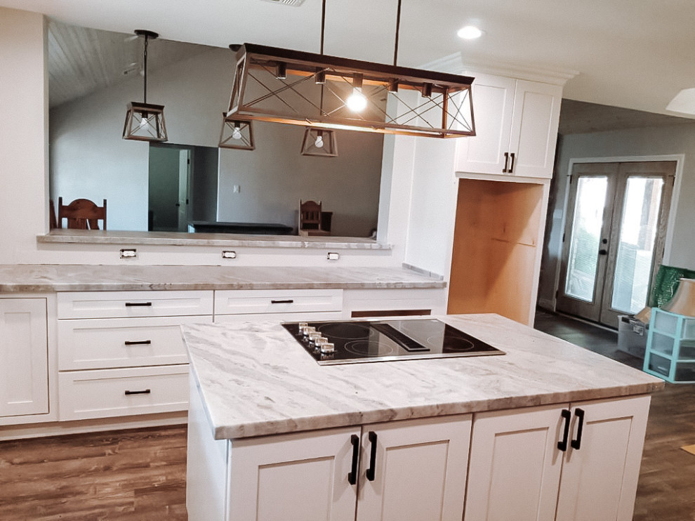 Example of a large transitional l-shaped medium tone wood floor and brown floor eat-in kitchen design in Houston with a farmhouse sink, shaker cabinets, light wood cabinets, stainless steel appliances, an island and gray countertops