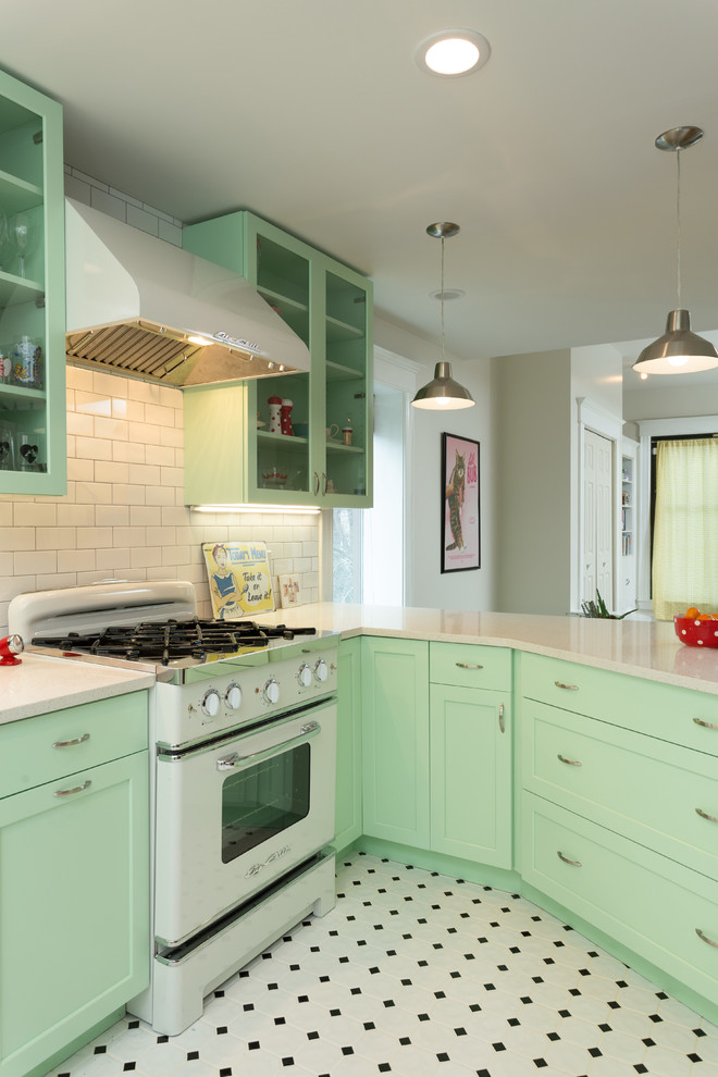 Inspiration for a mid-sized traditional l-shaped open plan kitchen in Chicago with shaker cabinets, green cabinets, white splashback, subway tile splashback, white appliances, a peninsula, a farmhouse sink, quartz benchtops and porcelain floors.