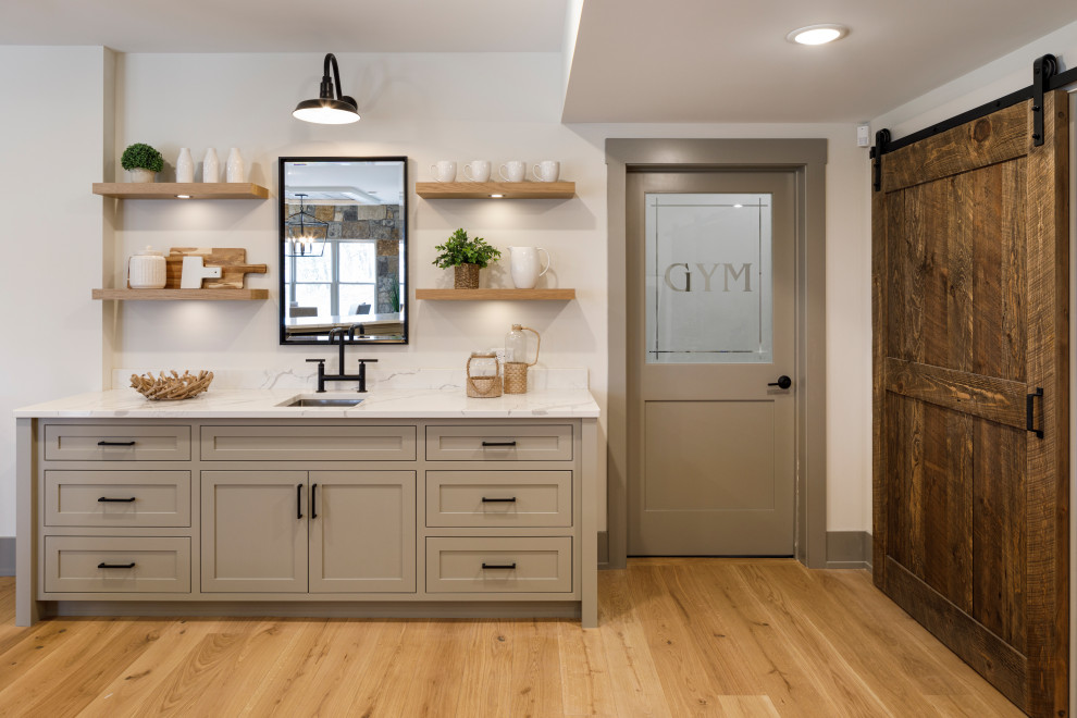 Transitional single-wall wet bar in Minneapolis with an undermount sink, shaker cabinets, beige cabinets, marble benchtops, multi-coloured splashback, medium hardwood floors, brown floor and multi-coloured benchtop.