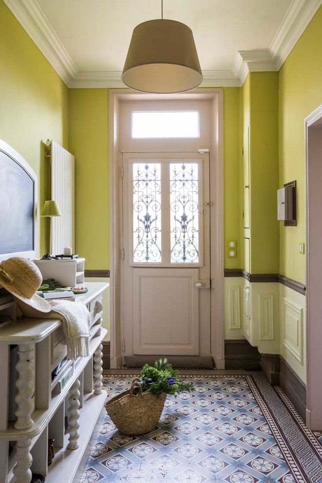 This is an example of a mid-sized country foyer in Paris with green walls, terra-cotta floors, a dutch front door, a purple front door and multi-coloured floor.