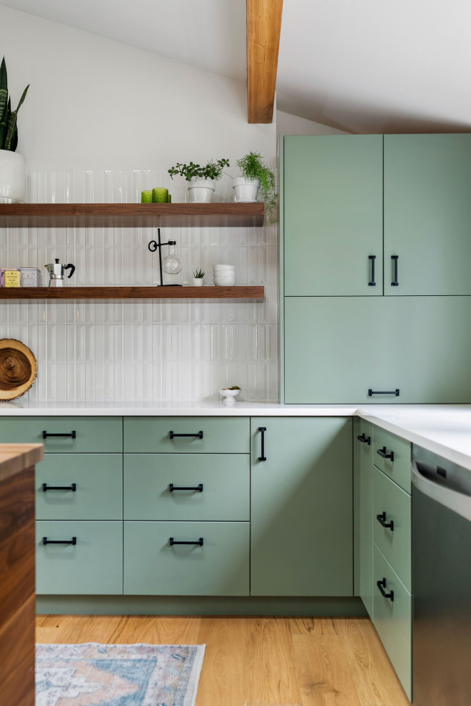 Design ideas for a large midcentury l-shaped open plan kitchen in Seattle with an undermount sink, flat-panel cabinets, green cabinets, quartz benchtops, white splashback, ceramic splashback, stainless steel appliances, medium hardwood floors, with island, white benchtop and vaulted.