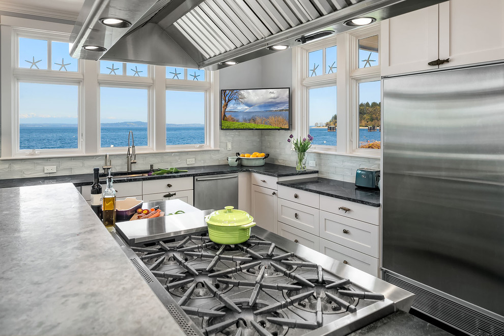 Beach style open plan kitchen in Seattle with an undermount sink, shaker cabinets, soapstone benchtops, glass tile splashback, stainless steel appliances, slate floors, with island, green floor and green benchtop.