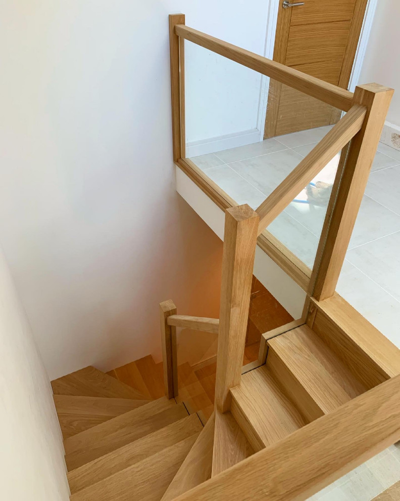 This is an example of a medium sized modern wood glass railing staircase in Devon with wood risers.