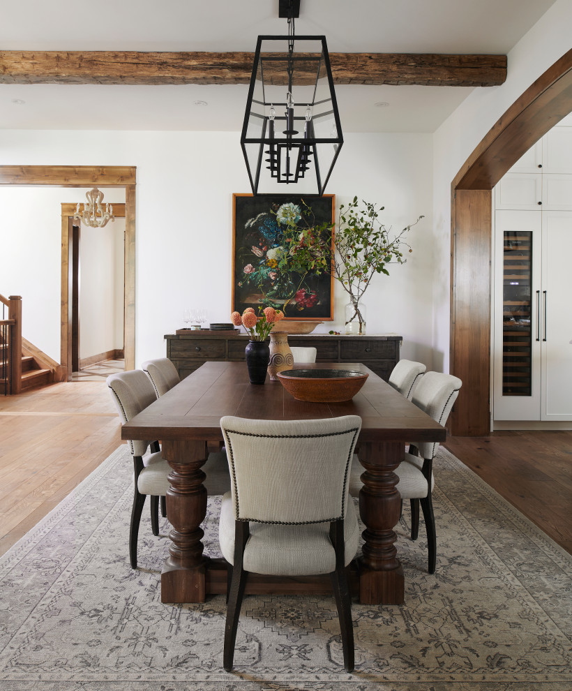 Idée de décoration pour une grande salle à manger ouverte sur la cuisine champêtre avec un mur blanc, un sol en bois brun, un sol marron et poutres apparentes.