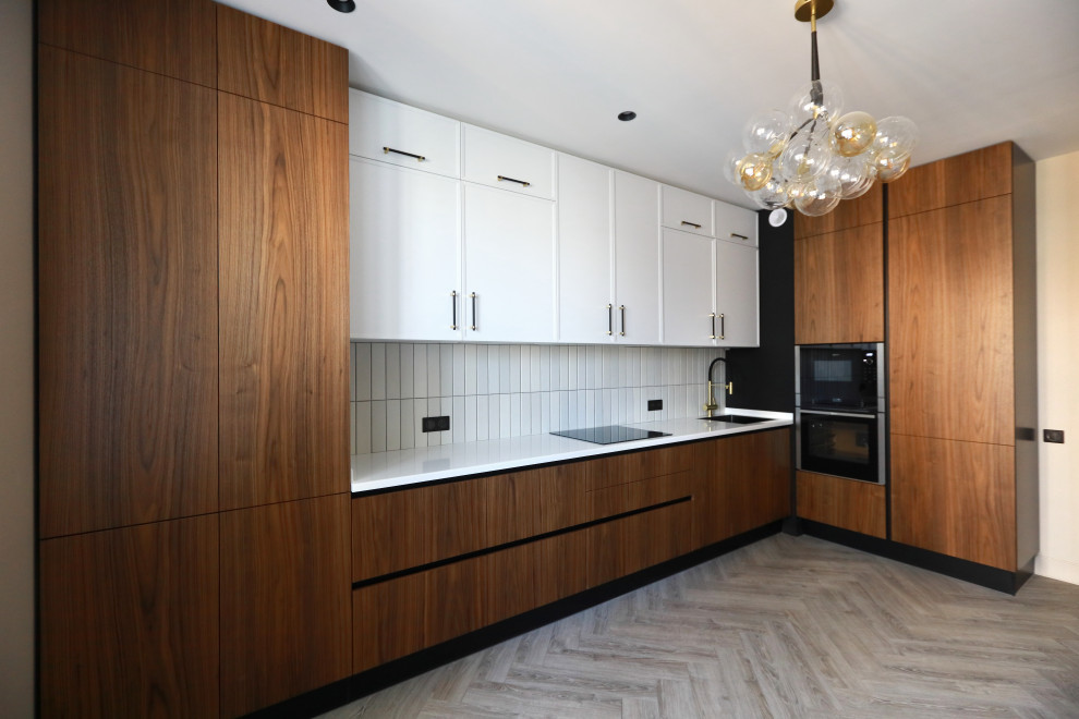 Inspiration for a large traditional l-shaped eat-in kitchen in Moscow with an undermount sink, flat-panel cabinets, white cabinets, quartz benchtops, white splashback, ceramic splashback, black appliances, medium hardwood floors, no island, beige floor and white benchtop.