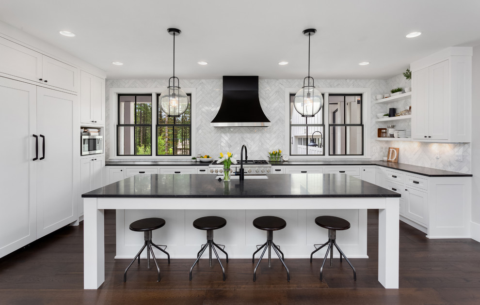 Transitional u-shaped kitchen in San Francisco with an undermount sink, shaker cabinets, white cabinets, white splashback, stainless steel appliances, dark hardwood floors, with island, brown floor and black benchtop.