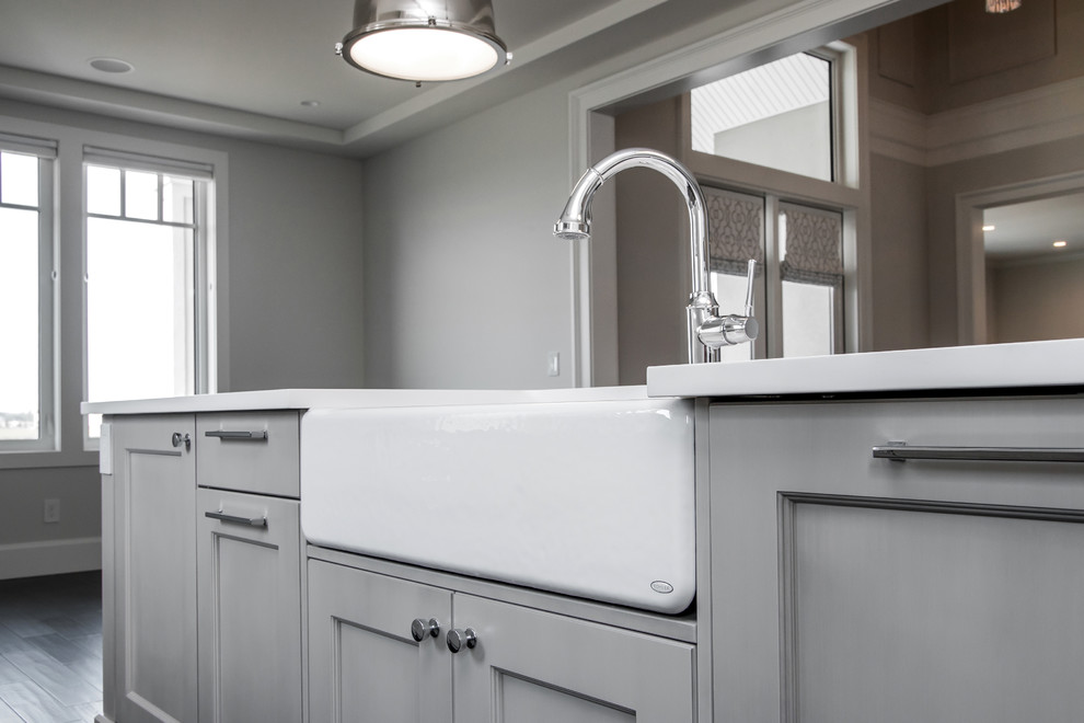 Inspiration for a large transitional l-shaped dark wood floor eat-in kitchen remodel in Calgary with a farmhouse sink, flat-panel cabinets, quartz countertops, white backsplash, subway tile backsplash, stainless steel appliances and an island