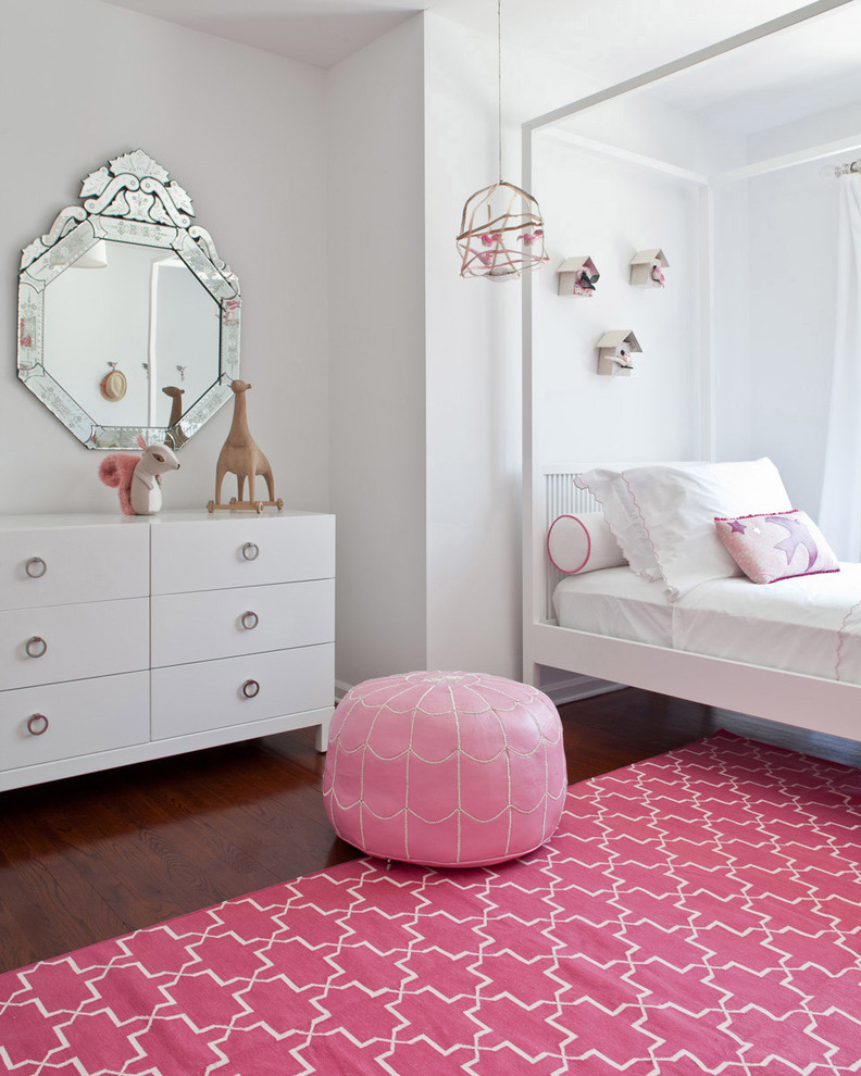 This is an example of a transitional kids' room for girls in New York with white walls and dark hardwood floors.