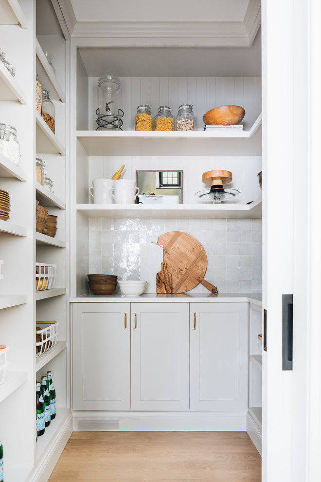 Photo of a small transitional u-shaped kitchen pantry in Chicago with shaker cabinets, grey cabinets, grey splashback, light hardwood floors, no island, white benchtop, quartz benchtops, terra-cotta splashback and brown floor.