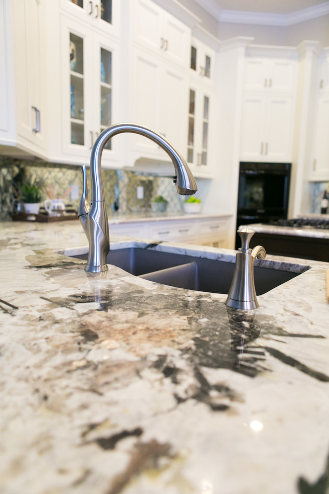 Example of a mid-sized transitional u-shaped light wood floor and brown floor open concept kitchen design in Orlando with an undermount sink, recessed-panel cabinets, white cabinets, granite countertops, mirror backsplash, black appliances and an island