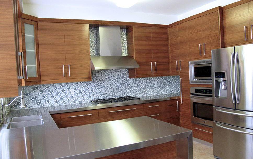 Mid-sized modern u-shaped eat-in kitchen in Toronto with an undermount sink, flat-panel cabinets, dark wood cabinets, stainless steel benchtops, blue splashback, mosaic tile splashback, stainless steel appliances, ceramic floors and a peninsula.