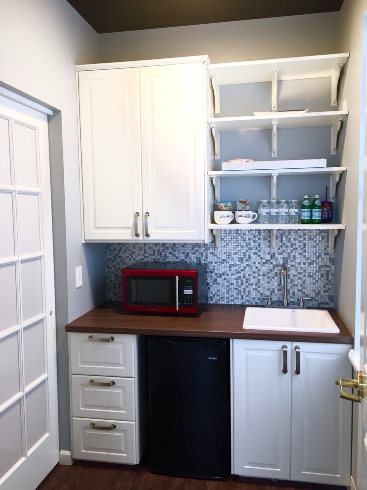 Photo of a small contemporary single-wall wet bar in Philadelphia with a drop-in sink, raised-panel cabinets, white cabinets, wood benchtops, blue splashback, mosaic tile splashback and dark hardwood floors.