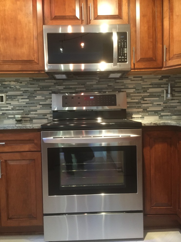 Example of a small transitional u-shaped ceramic tile eat-in kitchen design with an undermount sink, raised-panel cabinets, medium tone wood cabinets, granite countertops, glass sheet backsplash, stainless steel appliances and a peninsula