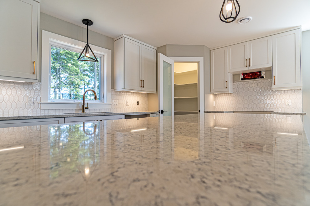 Inspiration for a mid-sized transitional light wood floor and beige floor eat-in kitchen remodel with an undermount sink, shaker cabinets, white cabinets, granite countertops, white backsplash, ceramic backsplash, an island and gray countertops