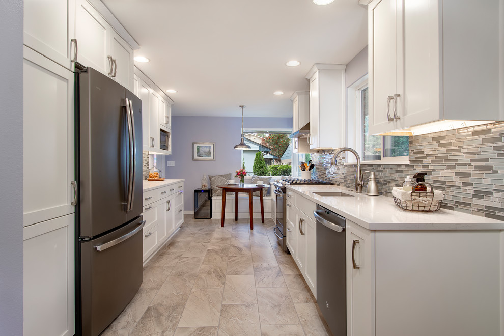 Example of a transitional porcelain tile and multicolored floor eat-in kitchen design in Seattle with an undermount sink, shaker cabinets, white cabinets, quartz countertops, multicolored backsplash, glass tile backsplash, no island and white countertops