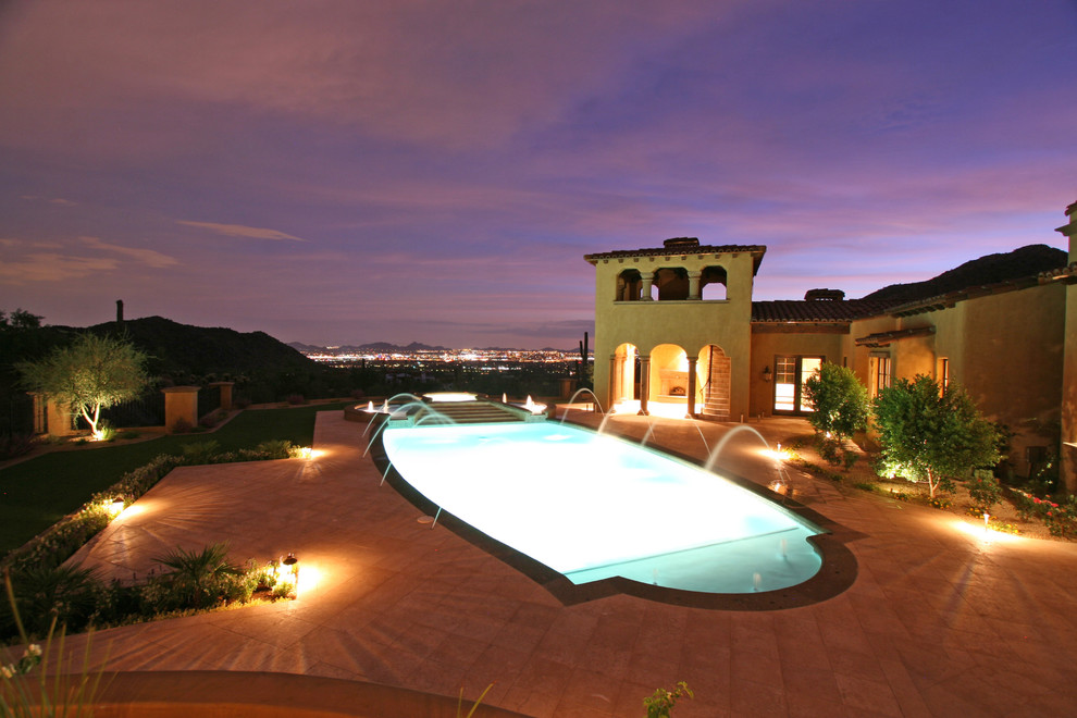 Inspiration for an expansive mediterranean backyard custom-shaped natural pool in Phoenix with a hot tub and natural stone pavers.