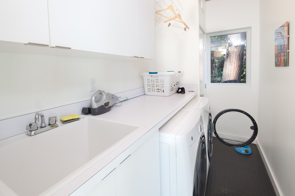 Inspiration for a midcentury galley laundry room in Seattle with a drop-in sink, flat-panel cabinets, white cabinets, white walls, a side-by-side washer and dryer and white benchtop.
