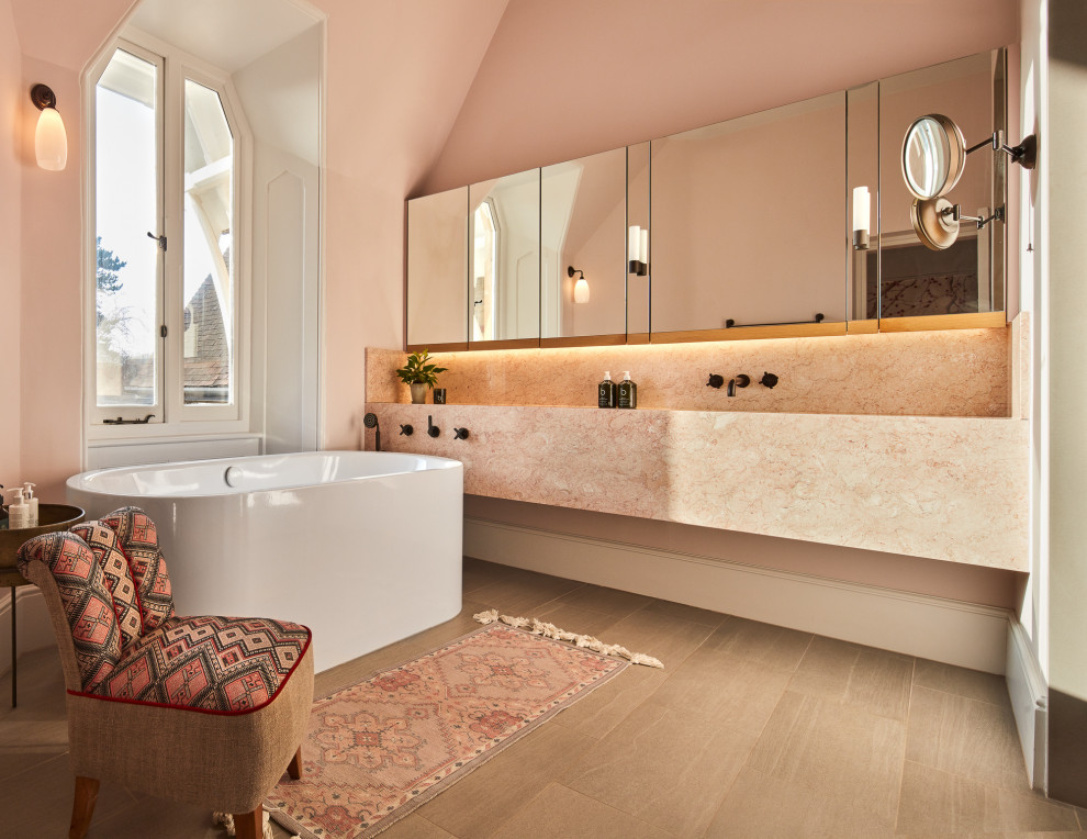 This is an example of a mid-sized contemporary master bathroom in London with a freestanding tub, pink walls, marble benchtops, pink benchtops, a double vanity and a floating vanity.